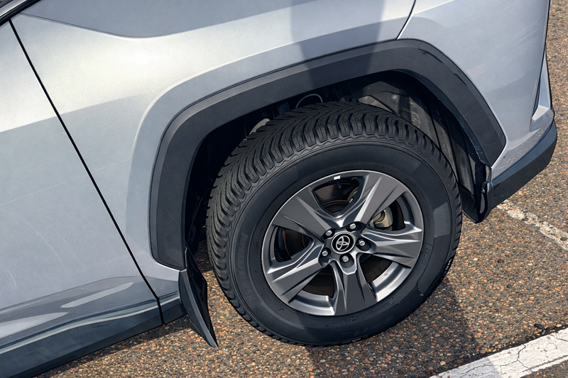 Car tire with mud flap on a gray vehicle