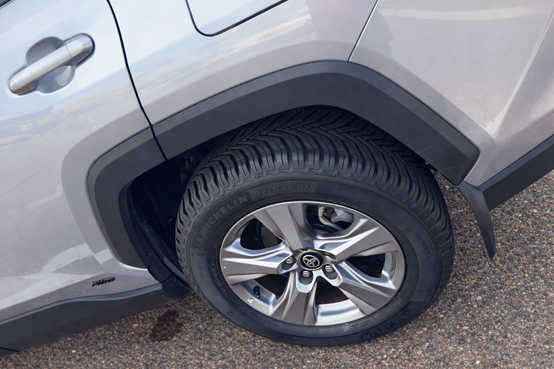 Close-up of a car tire with a visible brand logo on a gray vehicle.
