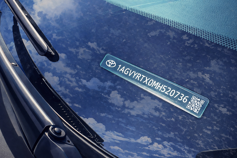 Car windshield with a Toyota logo and license plate against a blue sky.